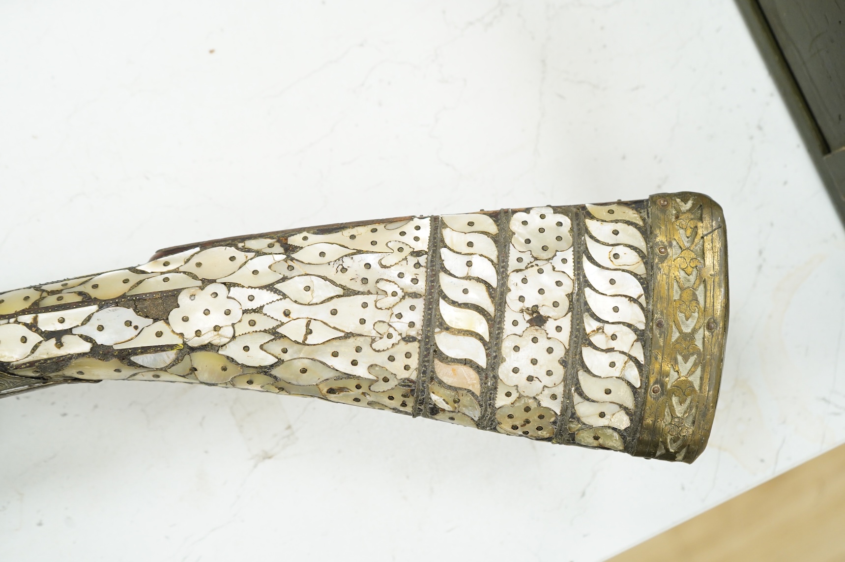 A Balkan miquelet flintlock gun with part octagonal Damascus twist barrel, silver inlaid at breach and muzzle, brass covered stock with shaped mother-of-pearl segments covering the butt, the side of stock inscribed ‘Piet